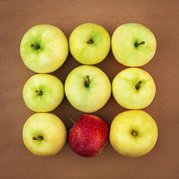 Сочные желто-зеленые яблоки в квадрате с одним красным яблоком. - Фото, изображение