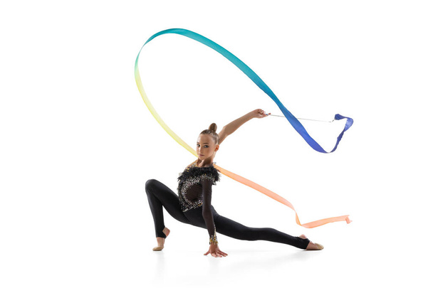 Portrait of little girl, rhythmic gymnastics artist training with colored ribbon isolated on white studio background. Concept of sport, action, aspiration - Foto, Imagem