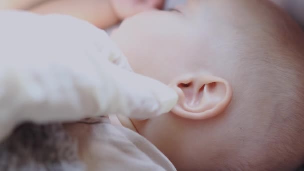 médicos mão na luva branca examina cheques bebê orelha infantil - Filmagem, Vídeo