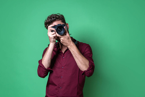 Αγόρι που κρατάει μια κάμερα χωρίς καθρέφτη και τραβάει μια φωτογραφία κοιτάζοντας μέσα από το ηλεκτρονικό σκόπευτρο. - Φωτογραφία, εικόνα