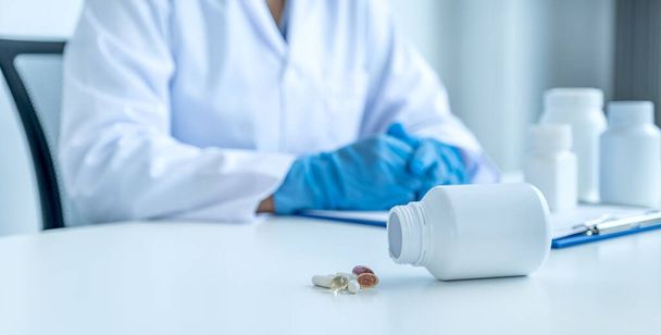 Medicijn pil en fles voor arts of apotheker met een recept bij de apotheek kantoor, gezondheidszorg en medische check-up concept. - Foto, afbeelding