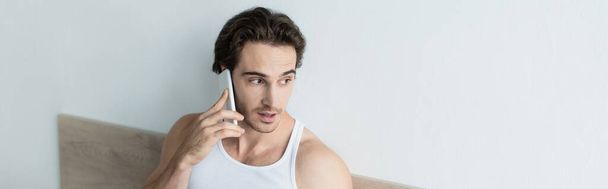 brunette man looking away while talking on smartphone in morning, banner - Photo, Image