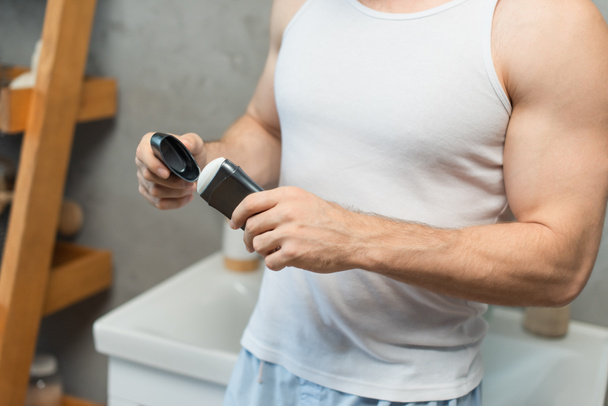 cropped view of man opening antiperspirant stick in bathroom - Photo, Image