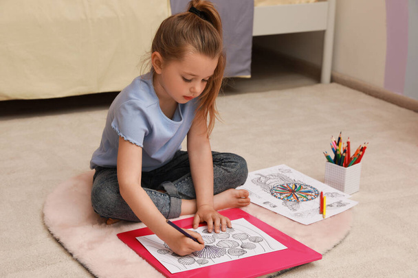 Little girl coloring antistress page on floor indoors - Foto, imagen