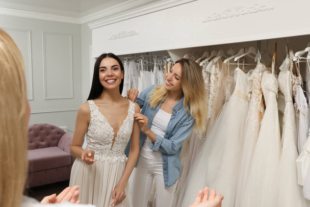 Bride with friends choosing wedding dress in boutique - Fotografie, Obrázek