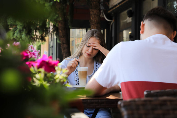 Young woman having boring date with guy in outdoor cafe - Φωτογραφία, εικόνα