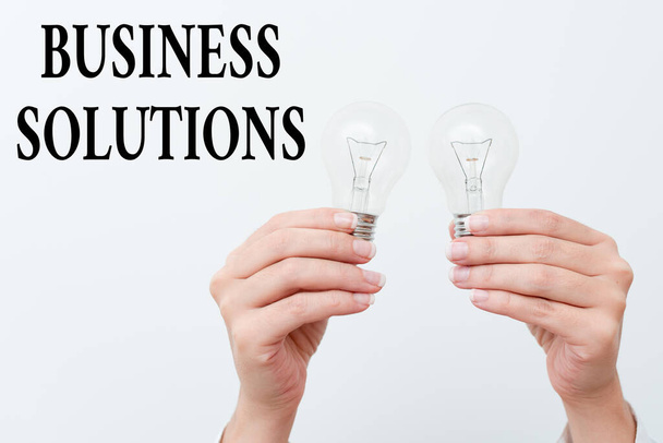 Merkki näyttää Business Solutions. Liiketoimintakonsepti ideoita käytetään auttamaan yritystä saavuttamaan tavoitteensa kaksi Hands holding lamppu esittelee tai esittelee uuden teknologian ideoita - Valokuva, kuva