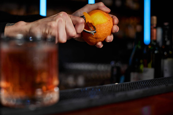 bartender makes a cocktail in a glass with orange peel - 写真・画像