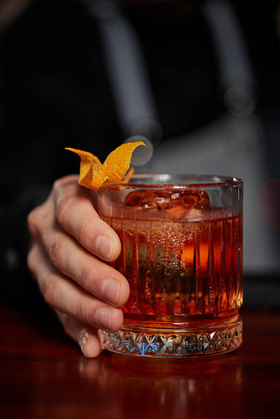 Barman holding out glass with alcoholic cocktail - Photo, image