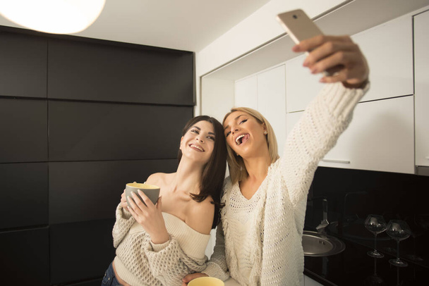 mladé krásné ženy, přičemž selfie s chytrým telefonem v kuchyni - Fotografie, Obrázek