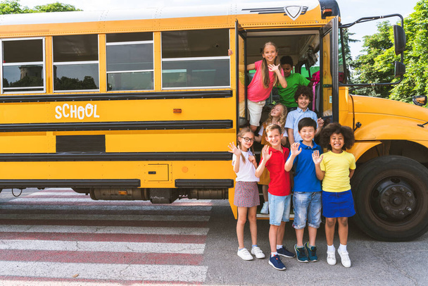 Grupo de jóvenes estudiantes que asisten a la escuela primaria en un autobús escolar amarillo - Los niños de la escuela primaria se divierten - Foto, imagen