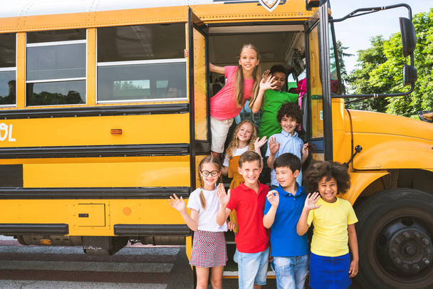 Grupo de jóvenes estudiantes que asisten a la escuela primaria en un autobús escolar amarillo - Los niños de la escuela primaria se divierten - Foto, Imagen