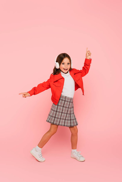 stylish child in headphones pointing with fingers on pink - Valokuva, kuva