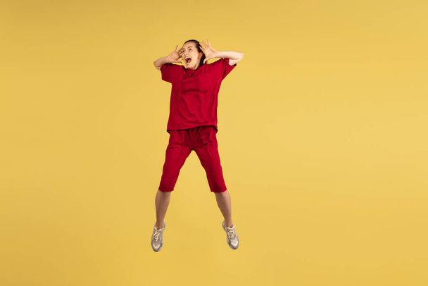 Portrait of young Caucasian woman jumping isolated on yellow background. - Фото, изображение