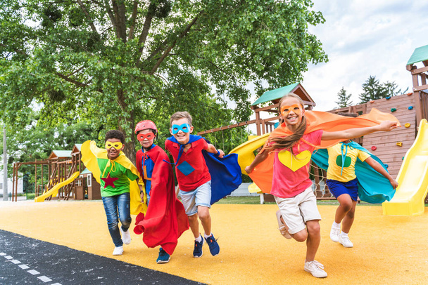 Multiracial group of young schooler wearing superhero costumes and having fun outdoors - Fotografie, Obrázek