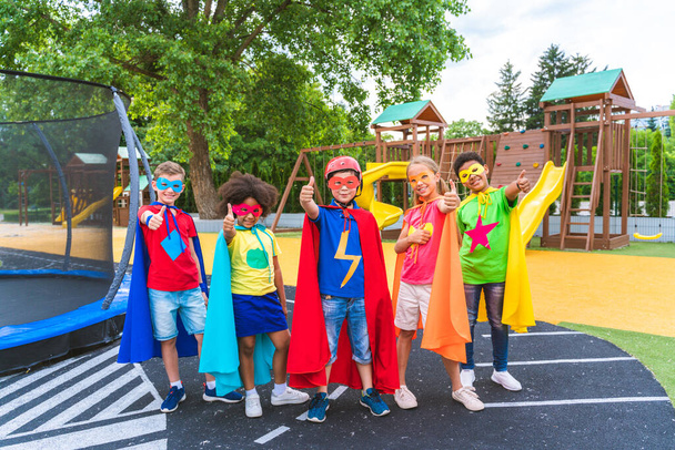 Multiracial group of young schooler wearing superhero costumes and having fun outdoors - Foto, afbeelding