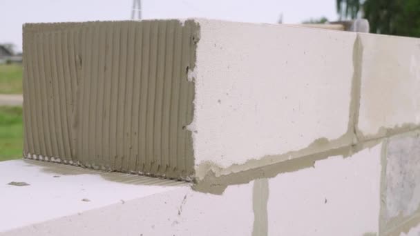 albañil colocación de la pared de un bloque, con una espátula para masilla al aire libre. - Metraje, vídeo