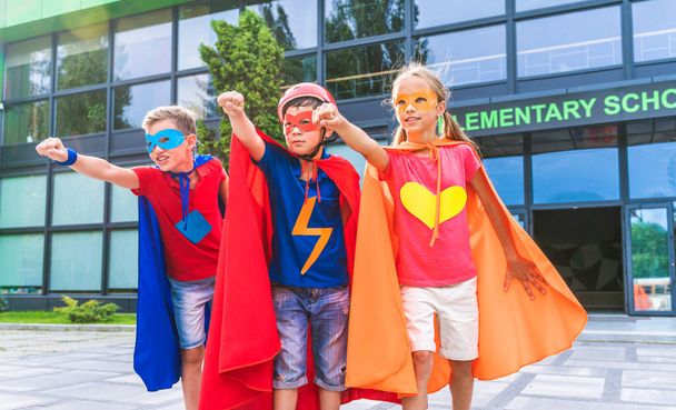Multiracial group of young schooler wearing superhero costumes and having fun outdoors - 写真・画像