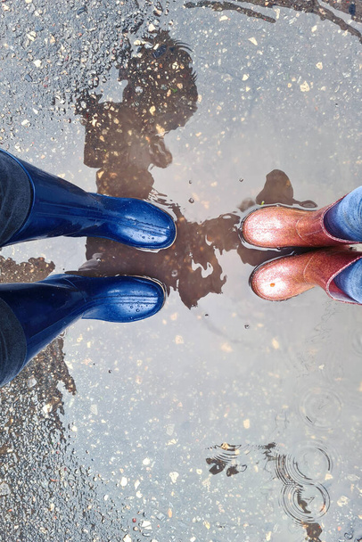 Mamá y su hija están caminando en botas de goma a través de los charcos en otoño - Foto, imagen