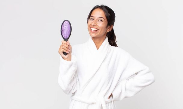 pretty hispanic woman wearing bathrobe and holding a hair brush - Foto, imagen