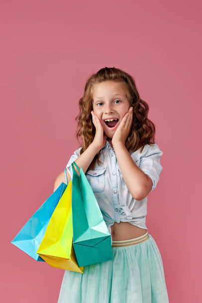 cute little caucasian child girl holds shopping bags - Foto, afbeelding