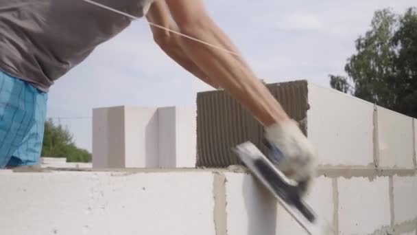 Maurer verlegt Wand aus einem Block, mit Spachtel für Spachtel im Freien. - Filmmaterial, Video