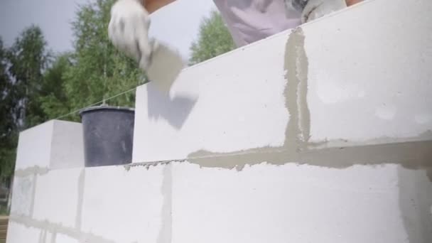 constructor aplica la composición adhesiva o solución con espátula a la estructura de la pared. - Metraje, vídeo