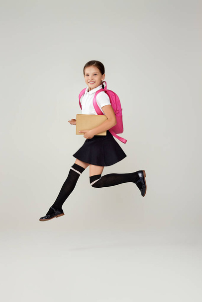 cute happy schoolgirl jumping up with backpack - Photo, image
