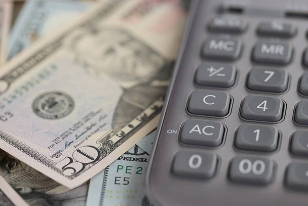 Szürke számológép feküdt dollár számlák közelkép - Fotó, kép