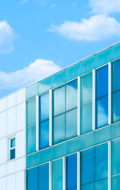 Vista a basso angolo di vetro blu e parete di piastrelle bianche del moderno edificio per uffici contro nuvole e sfondo cielo blu in cornice verticale - Foto, immagini