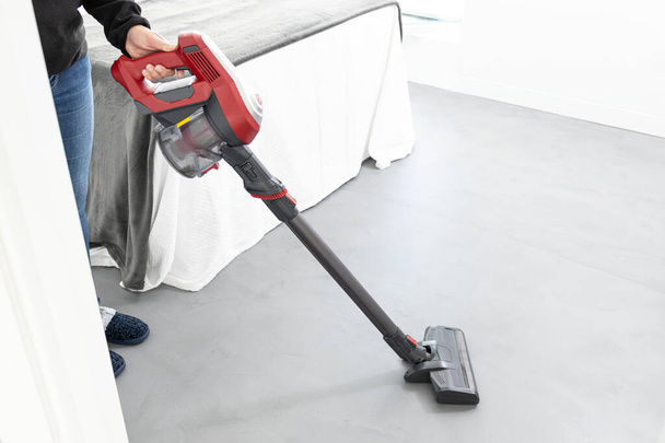 Woman cleaning a bedroom with a cordless vacuum cleaner. Copy space - Photo, Image