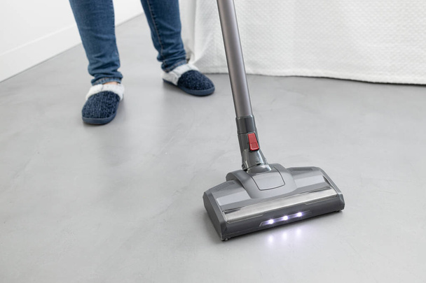 Woman cleaning with a cordless vacuum cleaner in a modern bedroom. Copy space - Foto, immagini