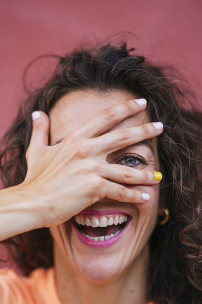 Χαμογελαστή γυναίκα που καλύπτει το μάτι με το χέρι - Φωτογραφία, εικόνα