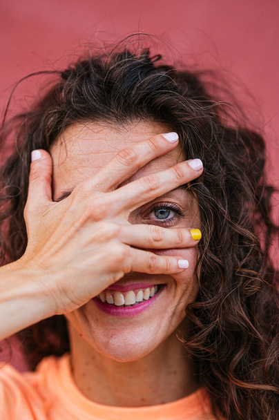 Lächelnde Frau bedeckt Auge mit Hand - Foto, Bild