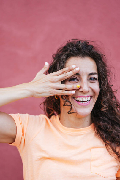 Smiling woman covering eye with hand - Foto, afbeelding