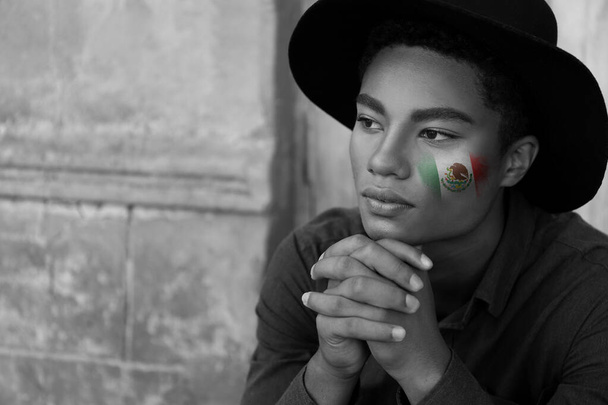 Stijlvolle jongeman met getrokken Mexicaanse vlag op gezicht - Foto, afbeelding