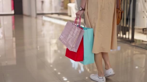 Beautiful woman carrying shopping bags in commercial center - Footage, Video