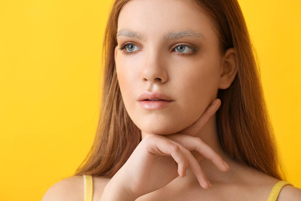 Schöne junge Frau mit gefärbten Augenbrauen auf farbigem Hintergrund - Foto, Bild