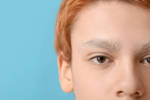 tiener jongen met geverfd wenkbrauwen op kleur achtergrond, closeup - Foto, afbeelding