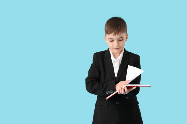 Little schoolboy reading book on color background - Zdjęcie, obraz