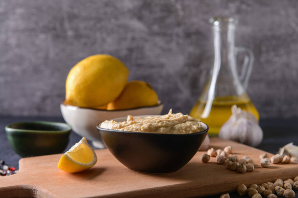 Schüssel mit leckerem Hummus, Kichererbsen und Zitronenscheibe auf dem Tisch - Foto, Bild