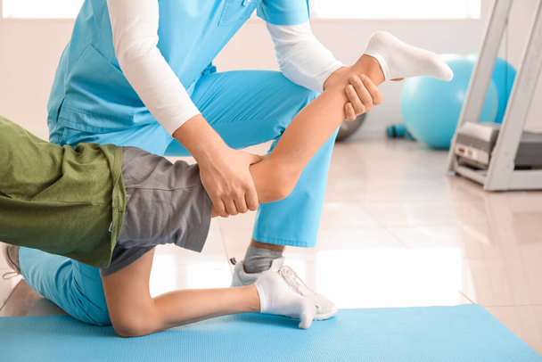 Fysiotherapeut werkt met jongen in revalidatiecentrum - Foto, afbeelding