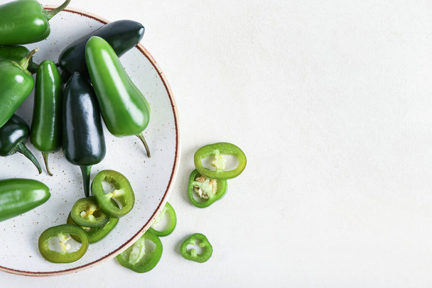 Plate with cut green jalapeno peppers on light background - Foto, immagini