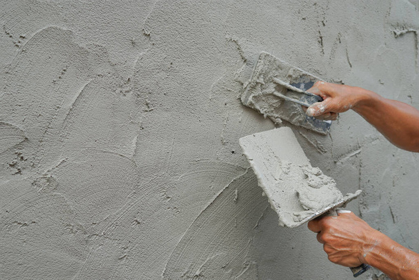 detalle texturizado de mortero de yeso, mientras que un trabajador enlucido pared de cemento en el sitio de construcción con espacio de copia, enfoque selectivo      - Foto, Imagen