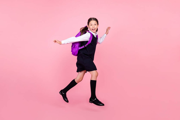 Full length body size photo schoolgirl jumping running on lesson on 1 september isolated pastel pink color background - Фото, изображение