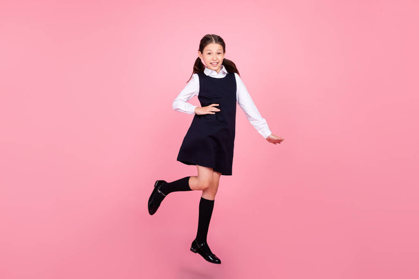Full length body size photo schoolgirl jumping up wearing uniform confident isolated pastel pink color background - Фото, изображение