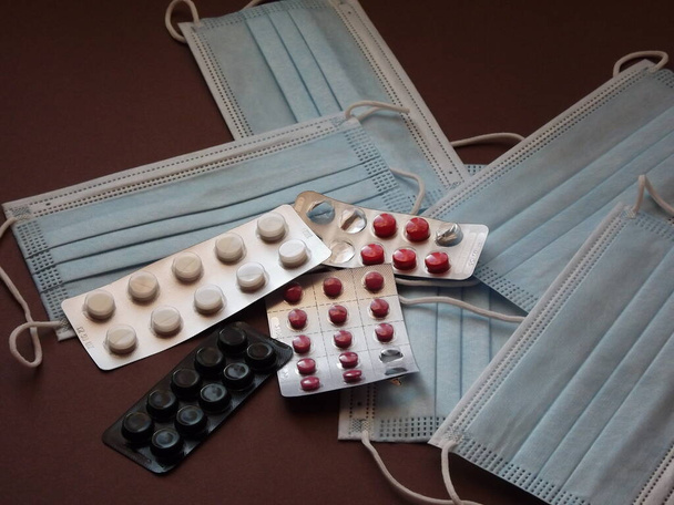 светло-голубые медицинские маски и красочный ковид 19 таблеток - Фото, изображение