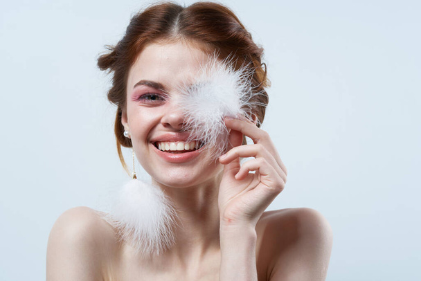 χαμογελαστή γυναίκα χνουδωτά σκουλαρίκια φωτεινά συναισθήματα μακιγιάζ φως φόντο - Φωτογραφία, εικόνα