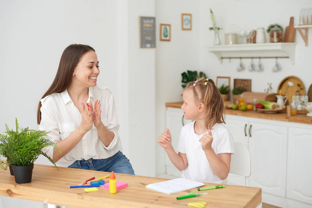 Mom and daughter finished doing their homework, rejoice and clap their hands. The concept of taking care of a child and helping with homework - Foto, Imagem