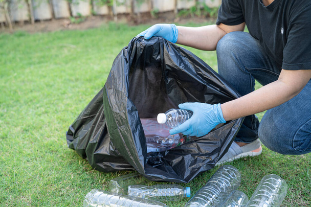 Azjatka wolontariuszka niesie plastikowe butelki z wodą do śmieci worków na śmieci w parku, recykling środowiska ekologicznego koncepcji. - Zdjęcie, obraz